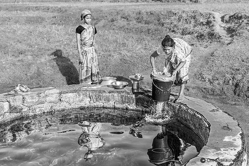 Munda lady waiting patiently as a Ghasi woman fetches drinking water from the Paata Daarhi at village Kudda, Jharkhand, India